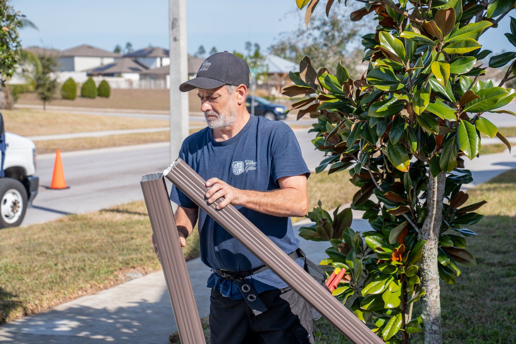 Installer carrying a brown downspout section to the house