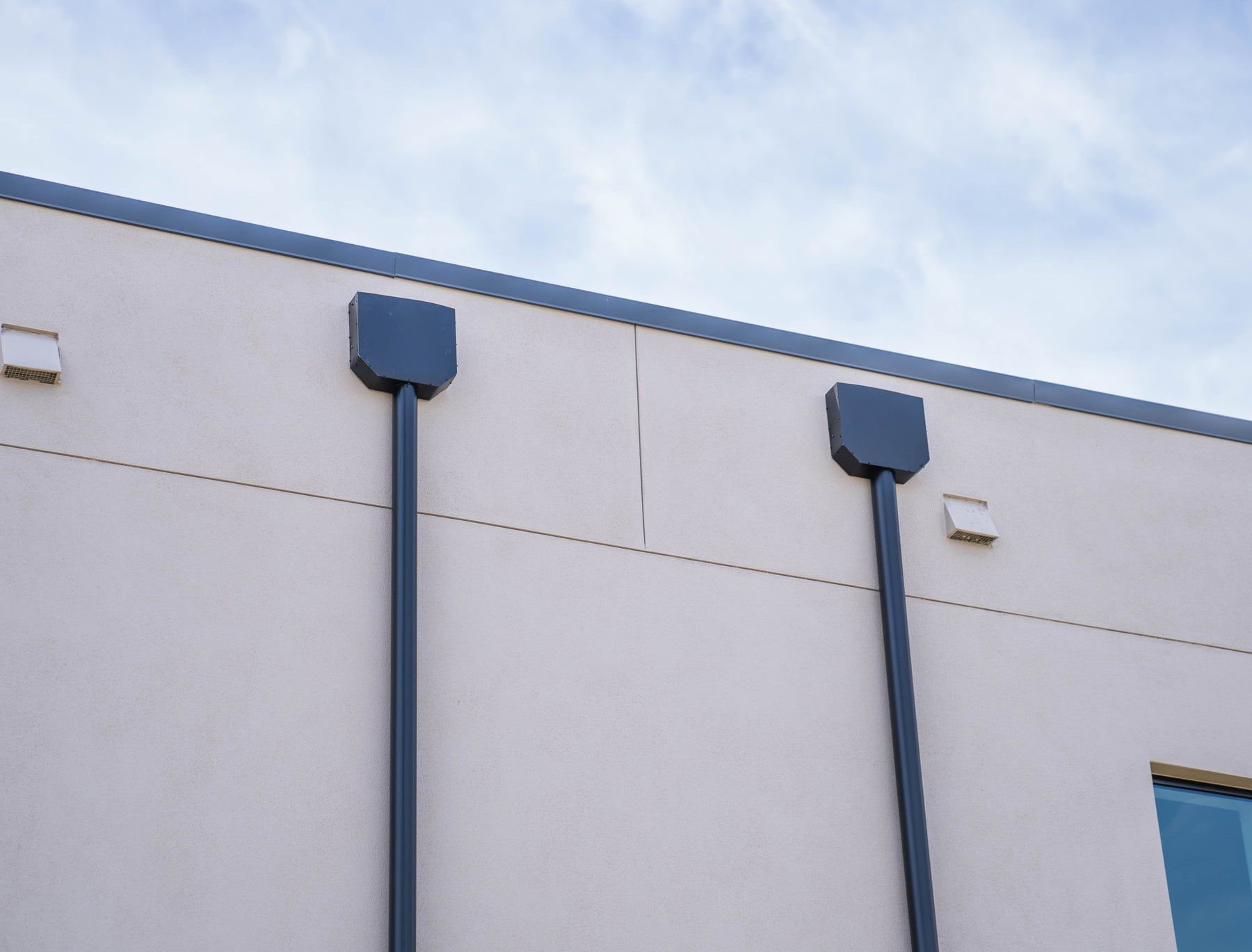 Custom scuppers and downspouts on a flat roof commercial wall