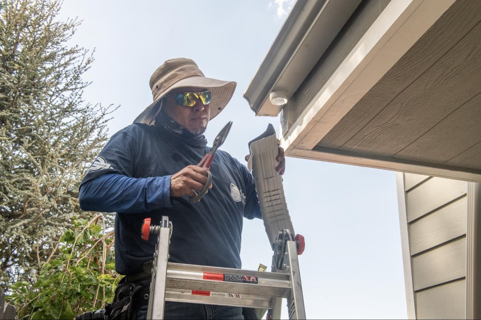 Crimping a downspout elbow on the ladder before it goes up