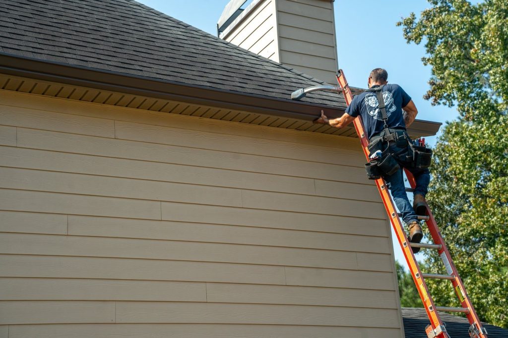 Installer hanging a gutter on a two story home