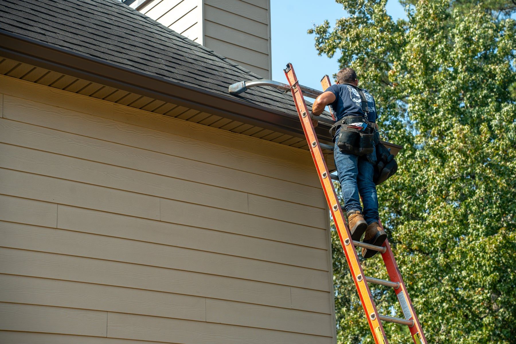 Installer on a ladder working along the roofline