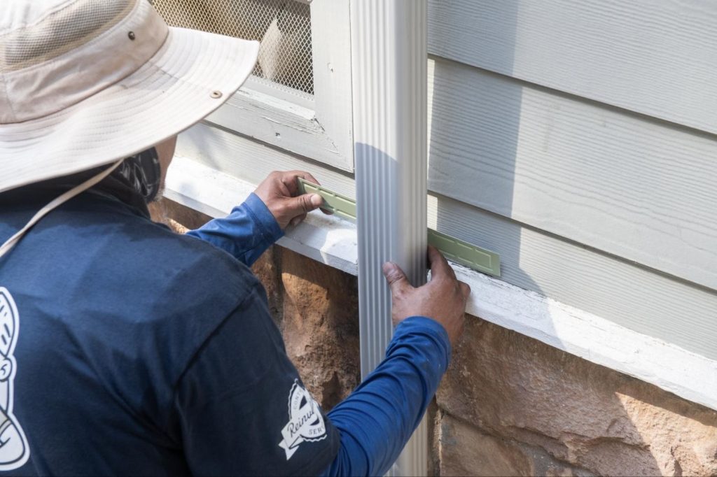 Measuring a downspout strap before fastening it