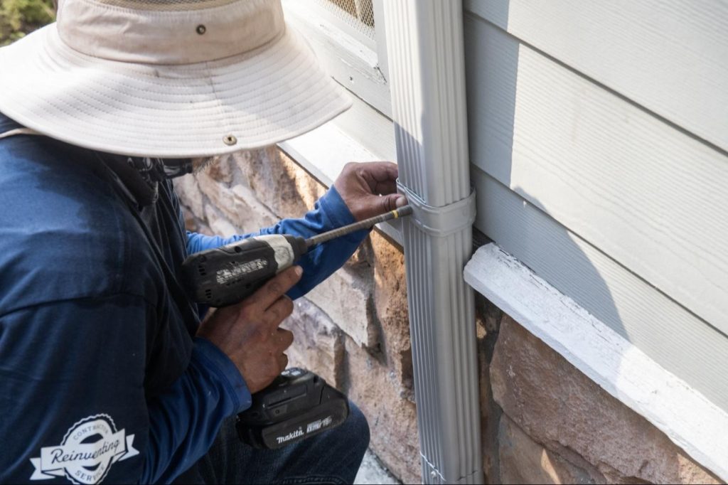 Strapping a new downspout tight to the wall